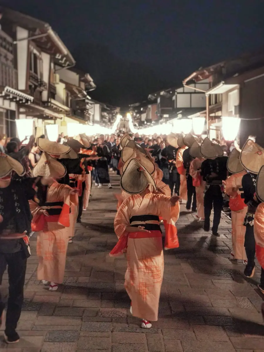 提灯の通りを流れていくおわらの踊り手の列